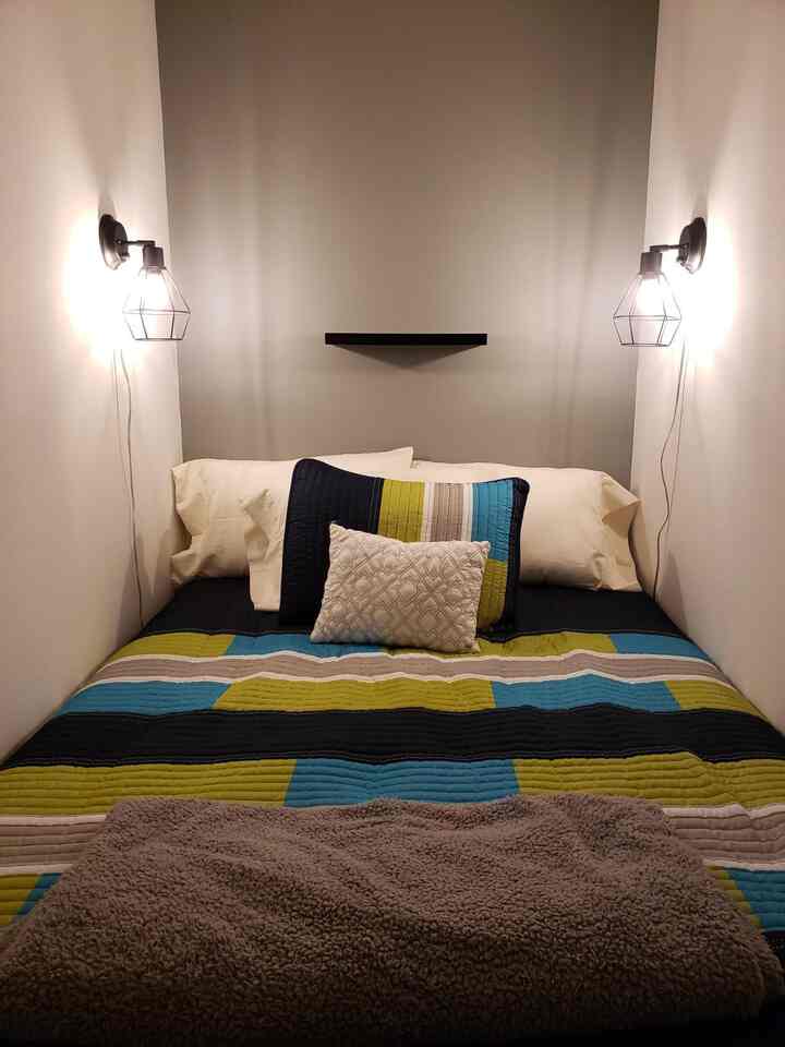 Gray-toned small bedroom with industrial cage wall sconces on both side walls, designed for a single household in a compact space