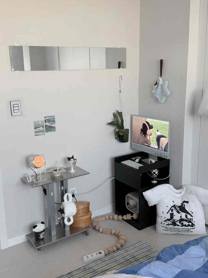 白とグレーのトーンの寝室、オブジェやモダンなサイドテーブルとデスクが配置された落ち着いた空間