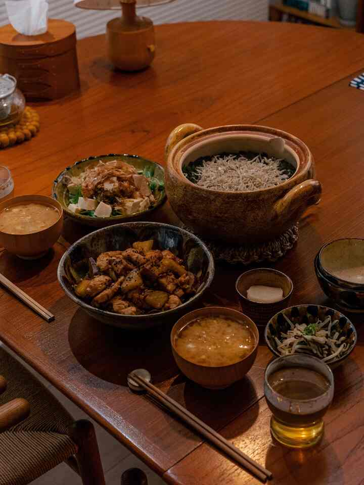 Natural-toned dining room featuring a round wooden table with ceramic bowls and a pot arranged for a cozy meal setting