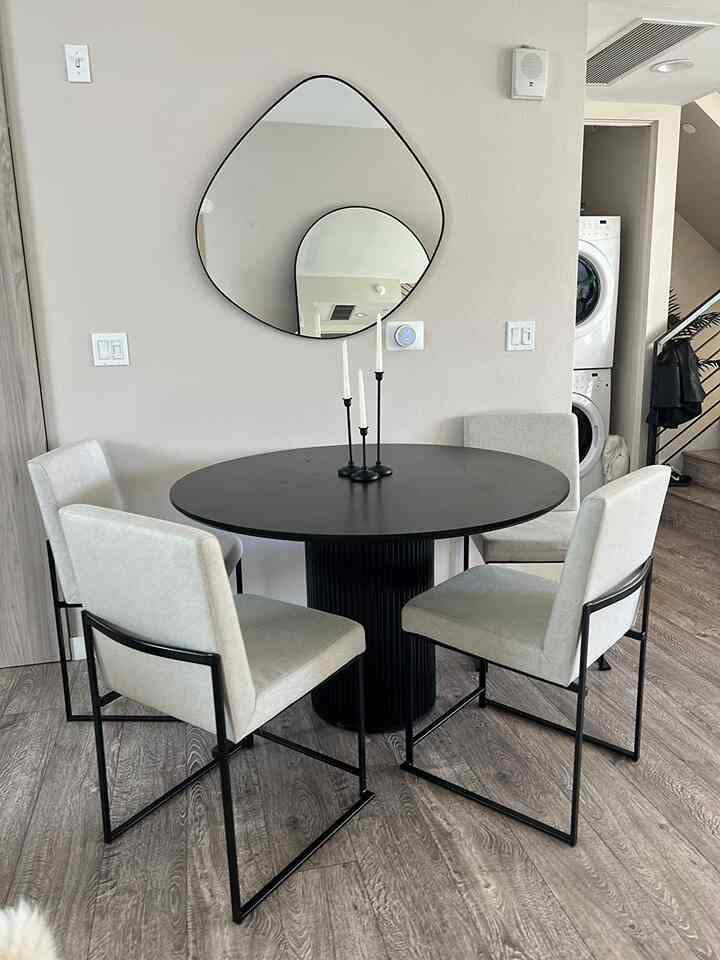 A modern dining room in black and white tones, featuring a round dining table and sleek chairs in a simple setting