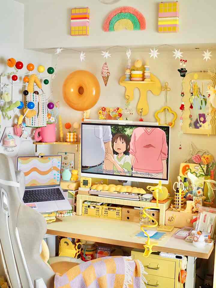 明るい黄色とパステル調が融合したコンパクトなホームオフィス空間、多彩な装飾とコンピュータ作業台が配置された印象的なインテリア