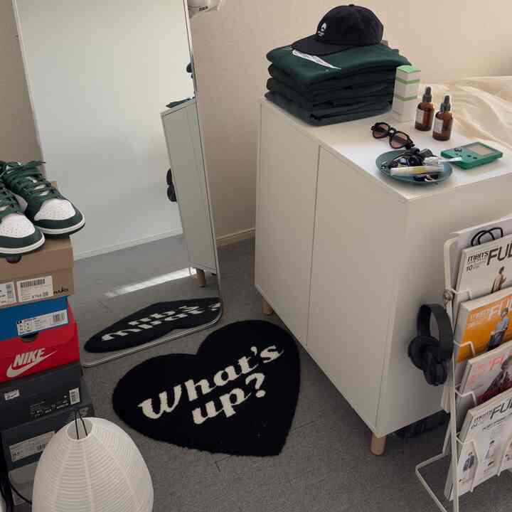 白と黒のトーンのワンルーム、白いキャビネットと大きな全身鏡が配置されたシンプルでミニマルなインテリア