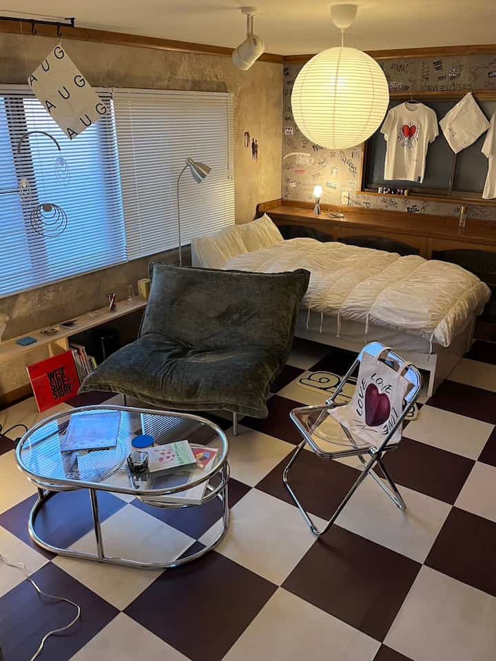 グレーと白のトーンのワンルーム寝室、モダンなソファとチェッカーフロアが調和するインダストリアルスタイルの雰囲気のあるインテリア