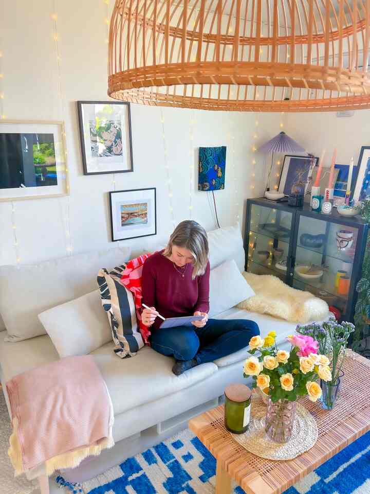 白とベージュの色調のリビング、広いコーナーソファと木製のコーヒーテーブル、壁のアートと温かい照明が配置された落ち着きのある空間