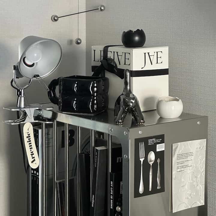 A modern interior corner featuring black and white candles and a mobile on a silver metallic shelf