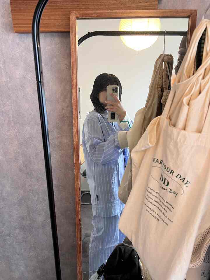 Pastel blue pajamas reflected in a large standing mirror in a single household loft bedroom featuring white tone accessories