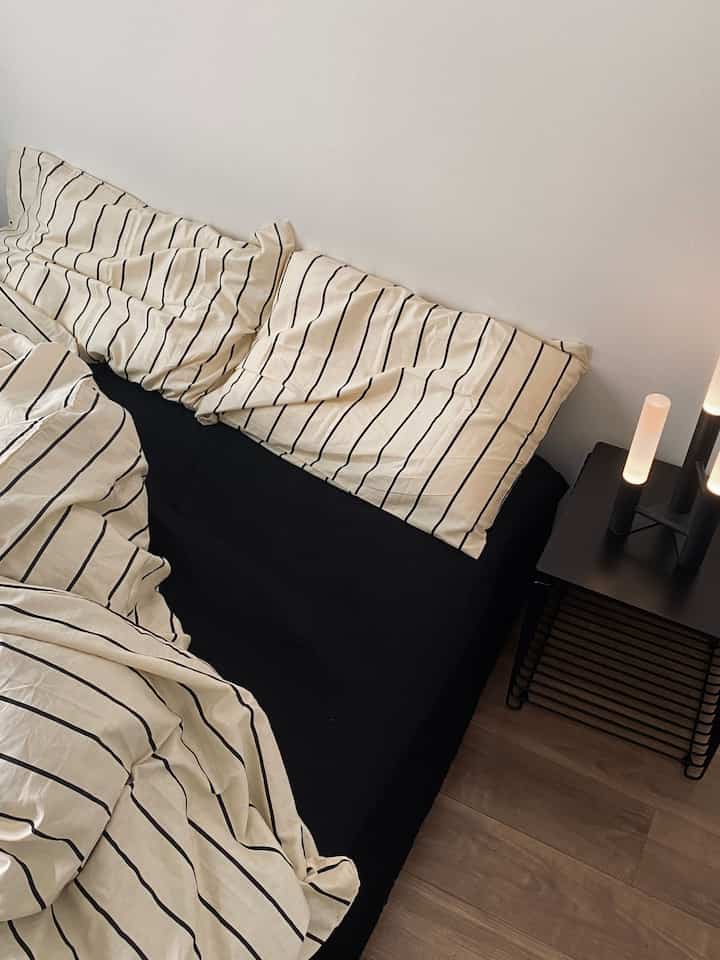 Simple and modern bedroom space featuring black and white striped bedding