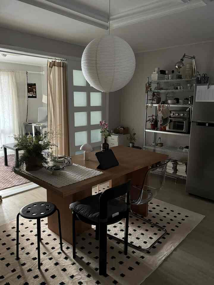 白と木目調のキッチン、モダンな雰囲気の中にダイニングテーブルと多様な椅子が配置された空間