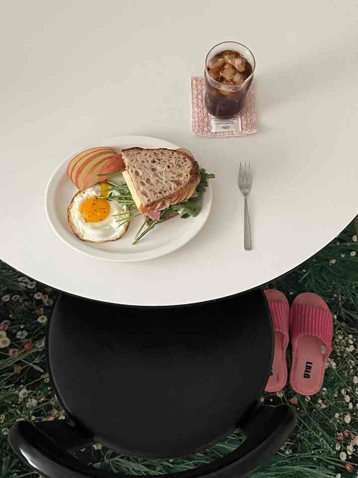 白と黒のトーンのワンルームダイニング、丸いテーブルにブランチセットとグラスが置かれたシンプルでナチュラルな雰囲気のインテリア