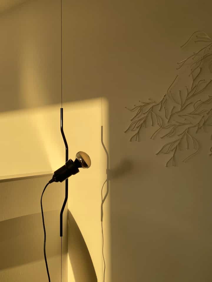 温かみのあるオレンジ色の光が差し込む子供部屋、中央に設置されたフロスのパレンティペンダントライトがある印象的なインテリア