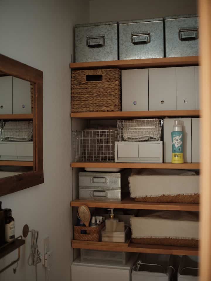 ナチュラルな木目調の棚と白い収納ボックスが配置された清潔感のあるバスルーム収納スペース