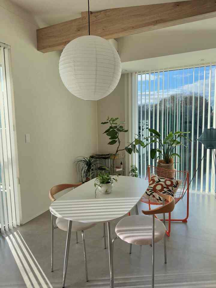 ナチュラルカラーと白を基調としたダイニング、木製チェアとペンダントライトが配置された明るく開放的なインテリア