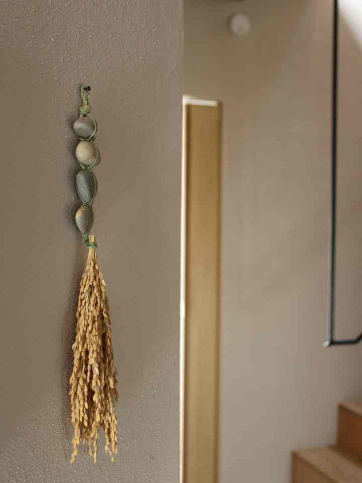 ナチュラルカラーと木目調の玄関壁に石と穀物の飾りが掛けられた雰囲気のある空間