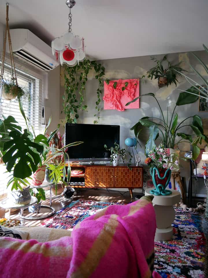 ナチュラルでヴィンテージなリビング、豊富な植物と木製テレビ台が配置された雰囲気のある空間