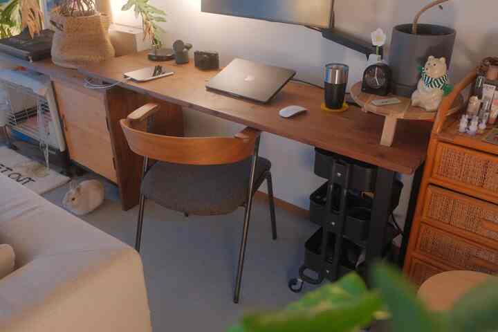 ナチュラルな色調のワークスペース、木製デスクとオフィスチェア、床に座るウサギがいる雰囲気のある空間