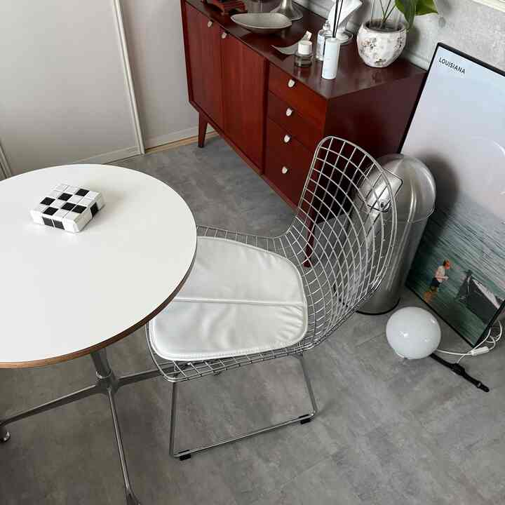 グレーの床と白いラウンドテーブル、木製キャビネットが配置されたナチュラルモダンな6畳の部屋