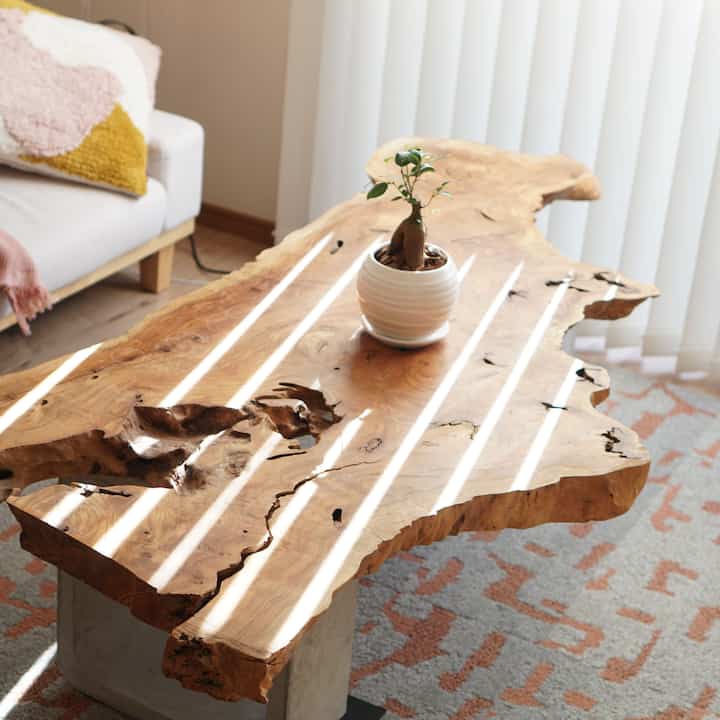 自然な木目調とベージュ色のリビング、ライブエッジ木製テーブルとクッションが配置された雰囲気のあるインテリア