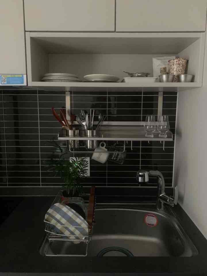 グレー調のキッチンシンクスペース、ステンレス製の壁収納棚と食器乾燥ラックが配置された清潔感のあるインテリア