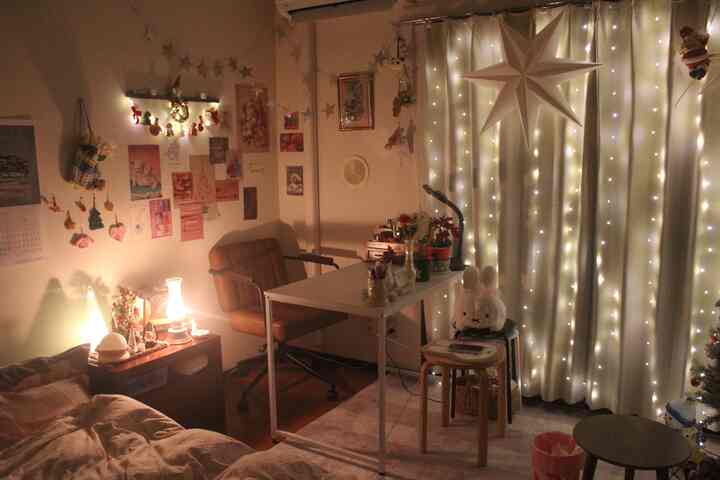 白いカーテンと茶色の家具が配置されたクリスマス装飾のある一人暮らしの部屋、温かみのある雰囲気