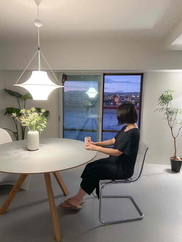 白を基調としたモダンなリビング、丸いダイニングテーブルとペンダント照明が印象的な空間