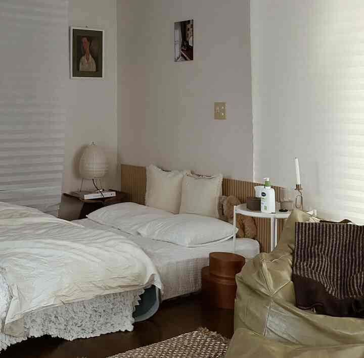 温かみのあるベージュ調の寝室、シングルベッドとソファ、サイドテーブル、柔らかな照明が配置されたナチュラルモダンなインテリア