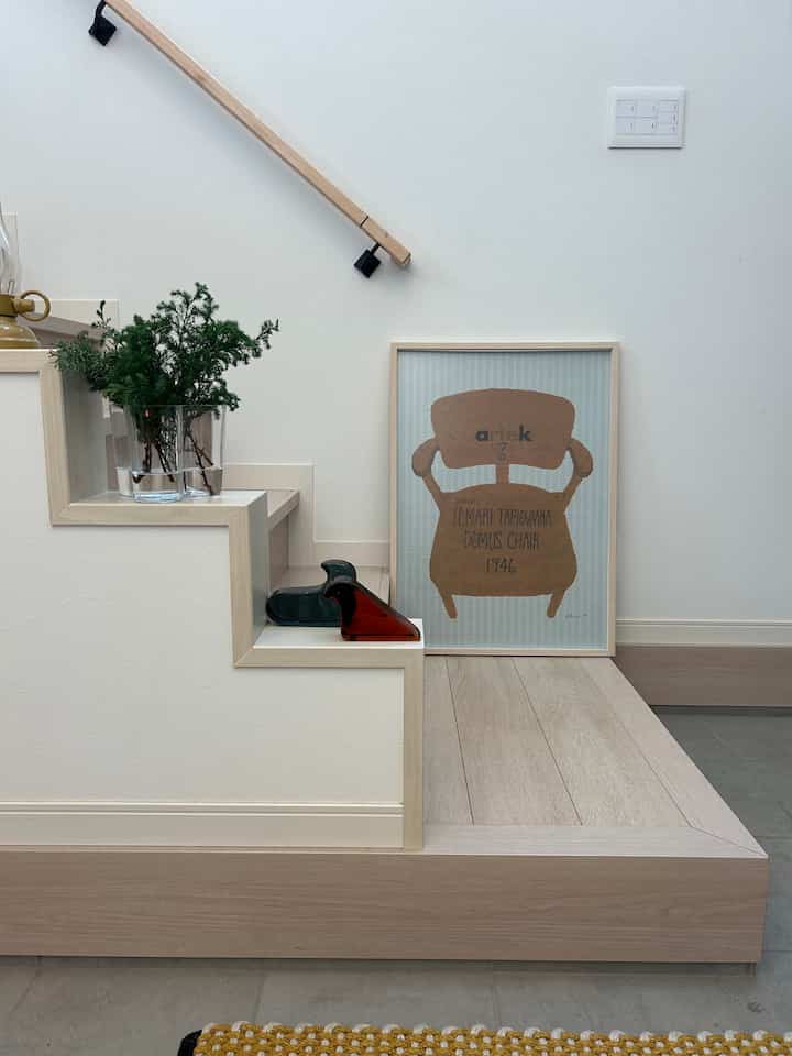 自然なウッドトーンと白い壁の玄関階段脇、収納スペースがある印象的な空間