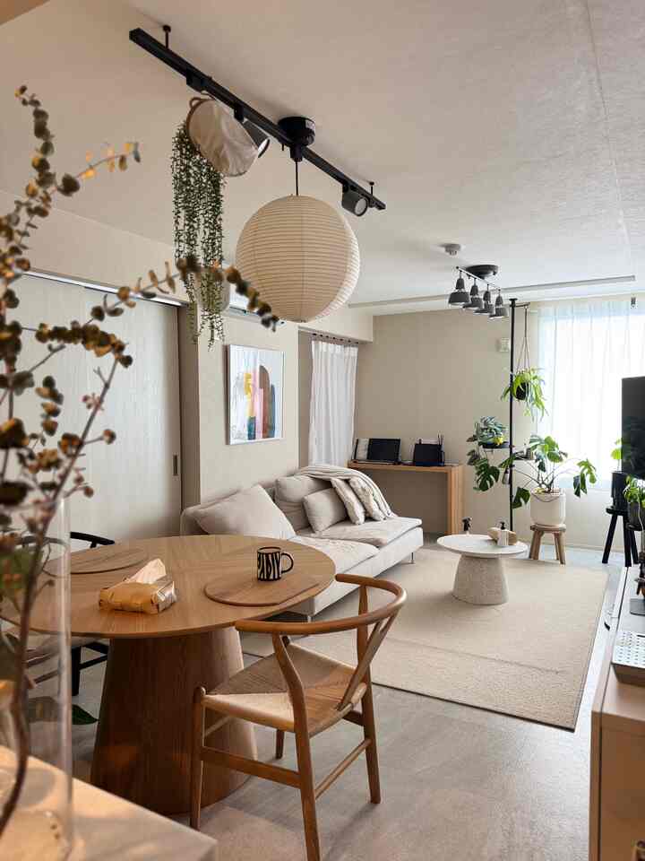 ナチュラルカラーの2LDKリビング、ミッドセンチュリーモダンと和モダンスタイルの円形ダイニングテーブルとソファ、植物が配置された雰囲気のある空間
