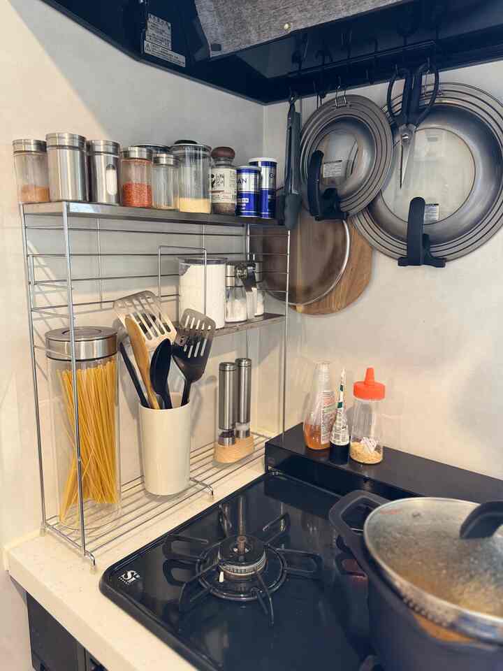 White walls and countertop kitchen featuring metal rack with spices and cooking utensils, neat organized space
