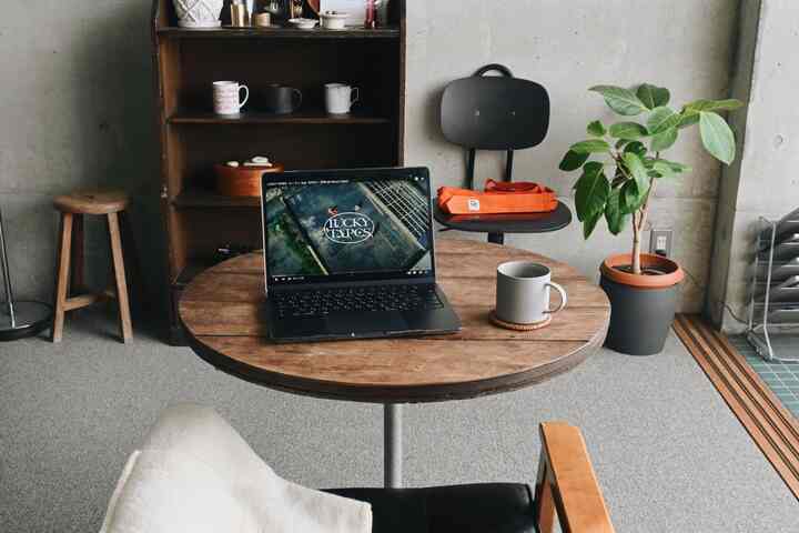 Natural-toned compact home office featuring a round wooden table with a laptop and mug, minimalistic modern decor