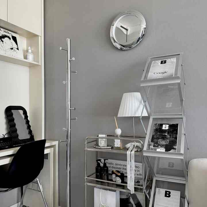 グレーのトーンが映えるミニマルなモダンホームオフィス、スチール家具とデスク、コートハンガーが配置された整理された空間
