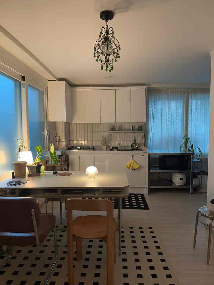 白と木目調のキッチンとダイニングルーム、ミッドセンチュリーモダン家具が配置された温かみのある清潔なインテリア