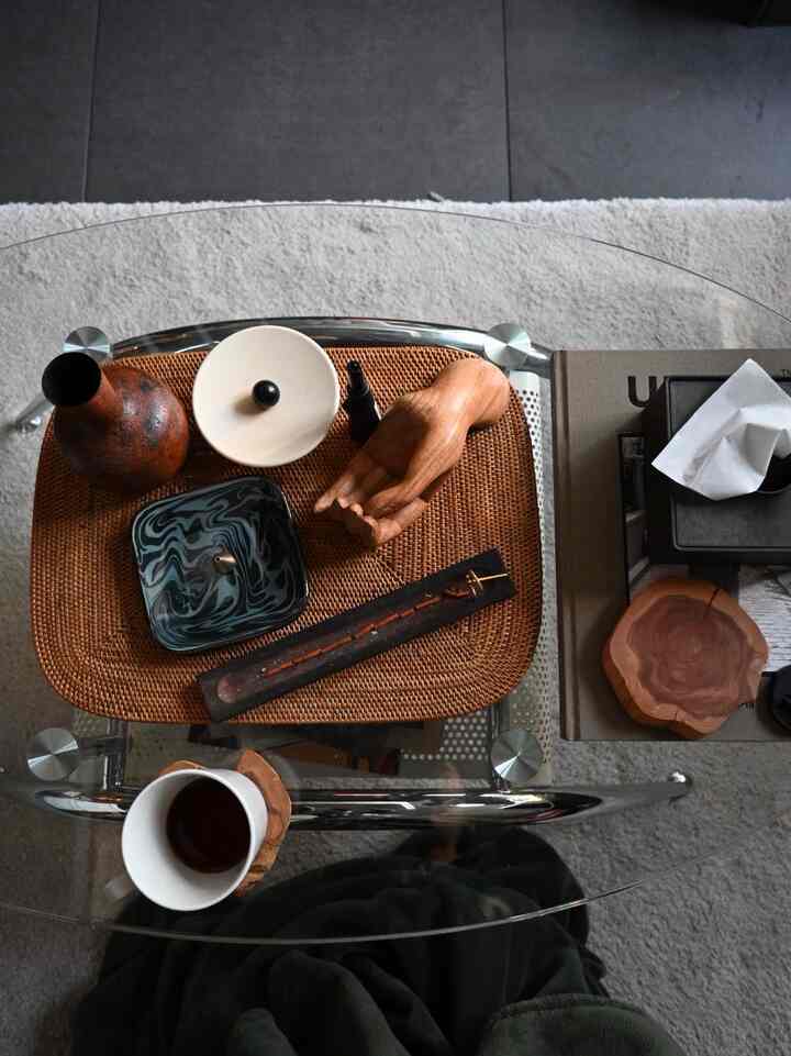 透明なガラスのコーヒーテーブルにブラウンのトレイと多様なオブジェが配されたミッドセンチュリーモダンなリビング空間