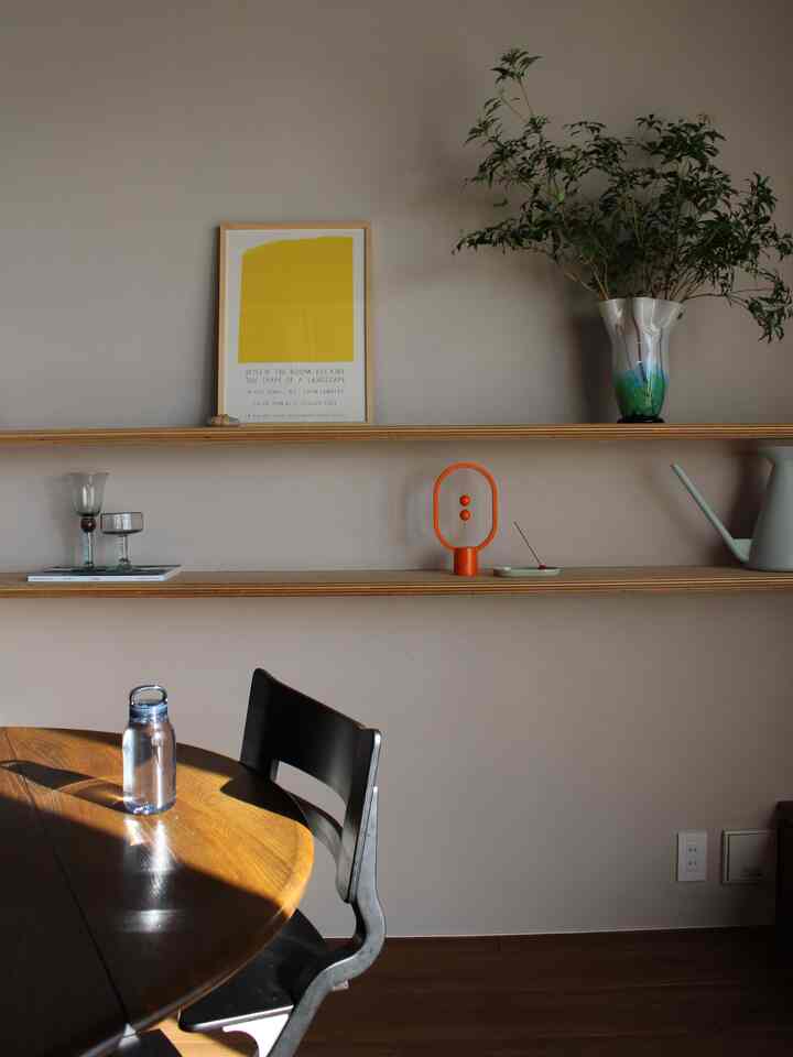 温かみのある木目調のダイニングルーム、透明なウォーターボトルが置かれた丸テーブルとダイニングチェアが配置されたシンプルな空間