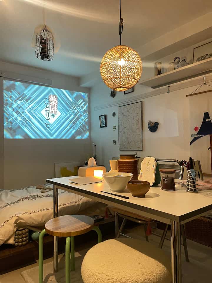 白と木目調の1Kワンルーム、一人暮らし向けのダイニング兼寝室スペース、落ち着いた暖かい雰囲気のインテリア