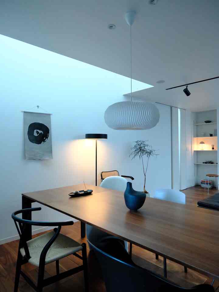 White-walled Wa-Modern dining room featuring a wood-tone dining table, pendant light, and floor lamp with cozy atmosphere