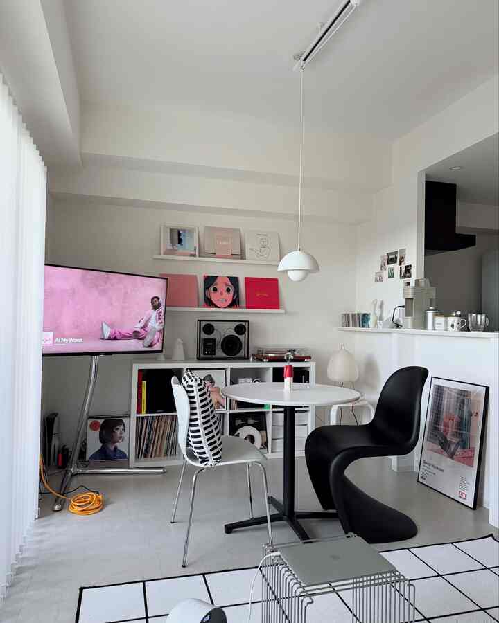 白とピンクのトーンが映えるダイニングルーム、丸テーブルとモノトーンチェアが配置されたミニマルな雰囲気のインテリア