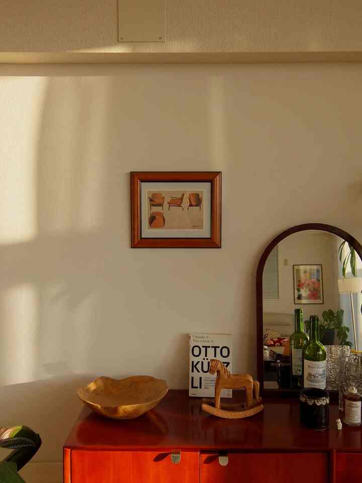 温かみのあるナチュラルカラーと木目調のリビング、レトロな雰囲気のサイドボードと木製オブジェが配置された印象的な空間