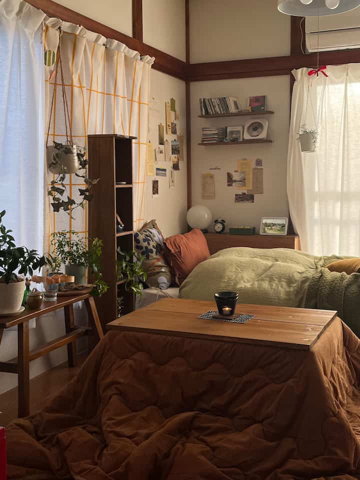 温かみのあるナチュラルカラーの一人暮らし寝室、こたつと植物が配置された雰囲気のある日本のアパート