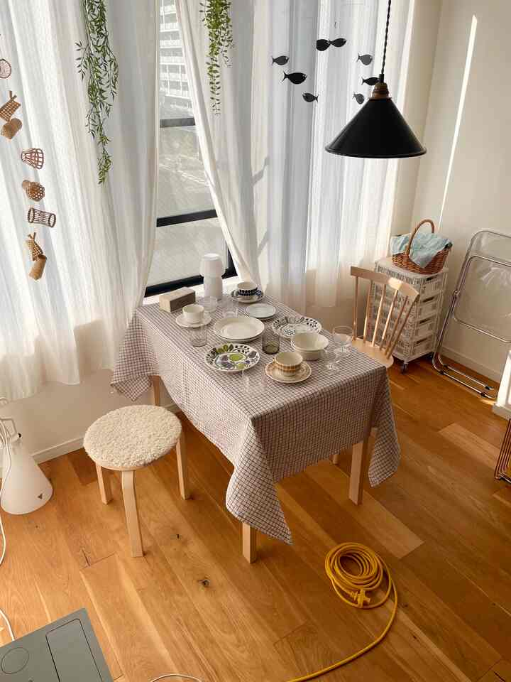 自然な木の床と暖かい北欧スタイルのダイニングテーブルと椅子が配置された、柔らかな自然光に包まれた居心地の良いダイニング空間