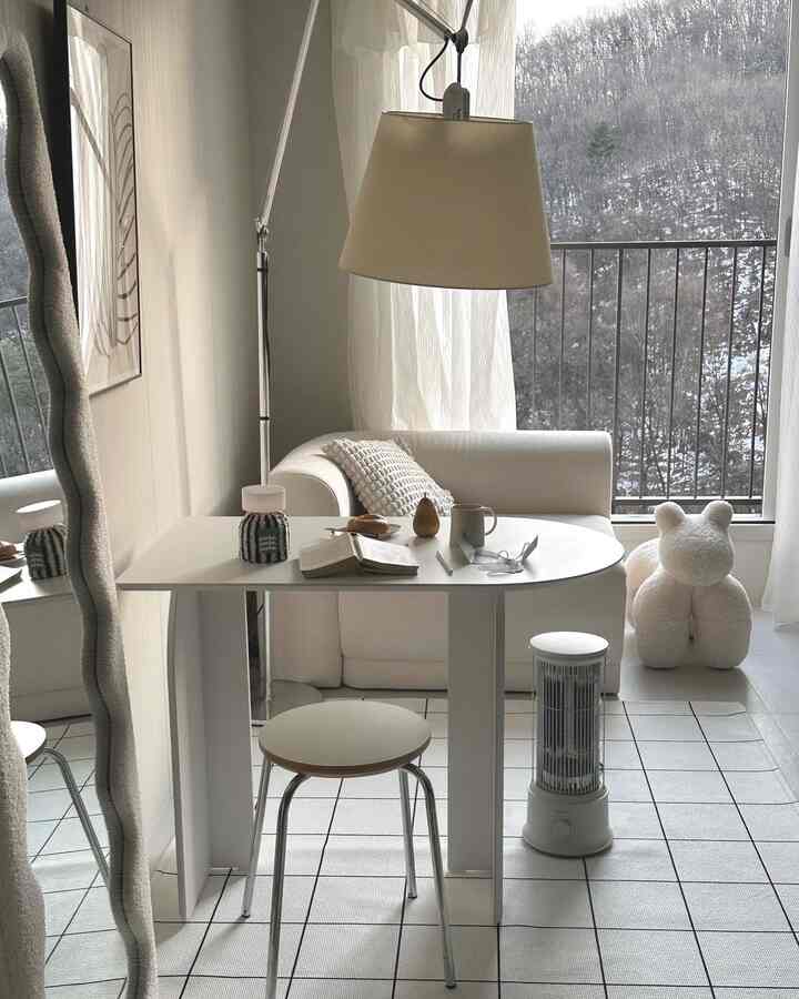 ベージュとホワイトのトーンの小さなリビング、ソファ、スツール、テーブルが配置されたシンプルで温かみのあるインテリア