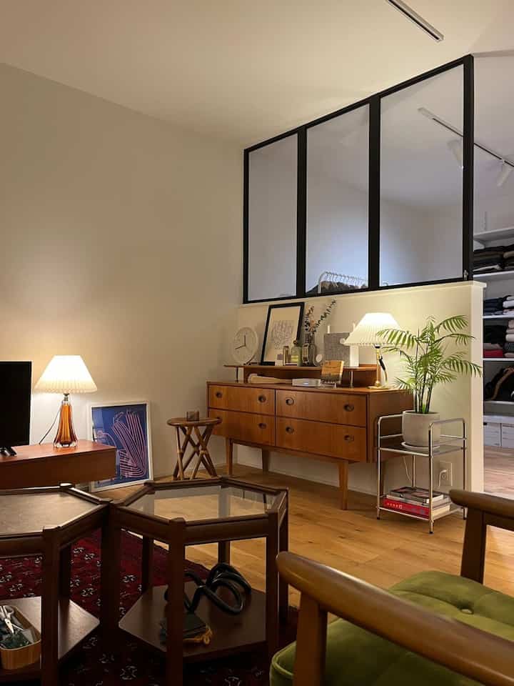 White-walled, wood-toned vintage-style walk-in closet and living room space with wooden furniture and plants