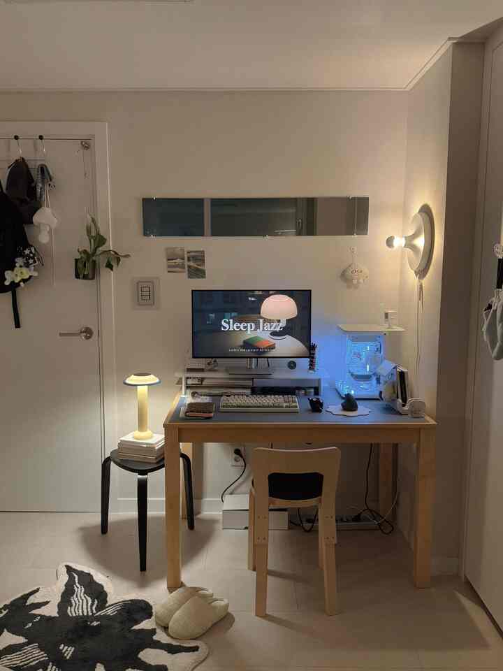 温かみのあるウッドトーンとムードライトがあるワンルームのホームオフィス、シンプルなミッドセンチュリーモダンのデスクスペース