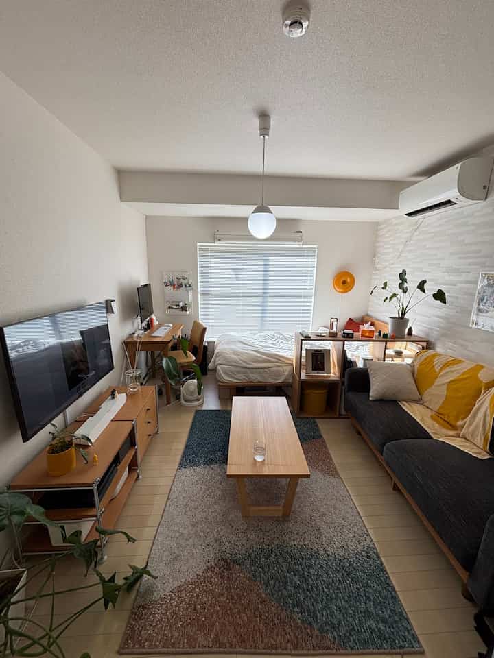 Natural-toned 7-tatami 1K studio featuring sofa, bed, desk, and organized cozy living space