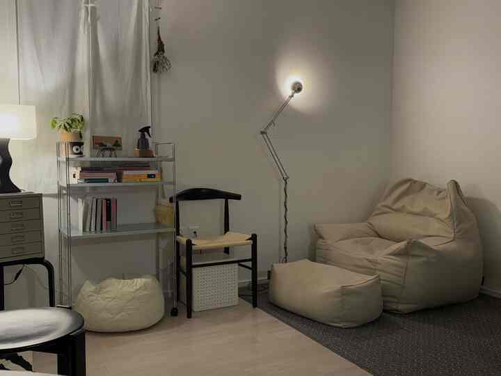 白い壁とベージュのビーズクッション、暗いラグが配置された雰囲気のあるリビング