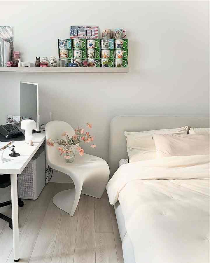 ホワイト調の寝室、シンプルなファブリックベッドとデスクにモニター、オフィスチェアが配置された清潔感のあるインテリア