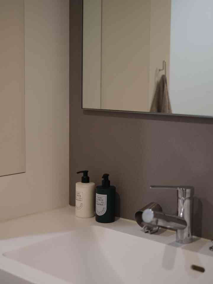 ベージュとホワイトのトーンのトイレ洗面スペース、シンプルでモダンなデザインの中にハンドウォッシュが置かれた清潔感のあるインテリア