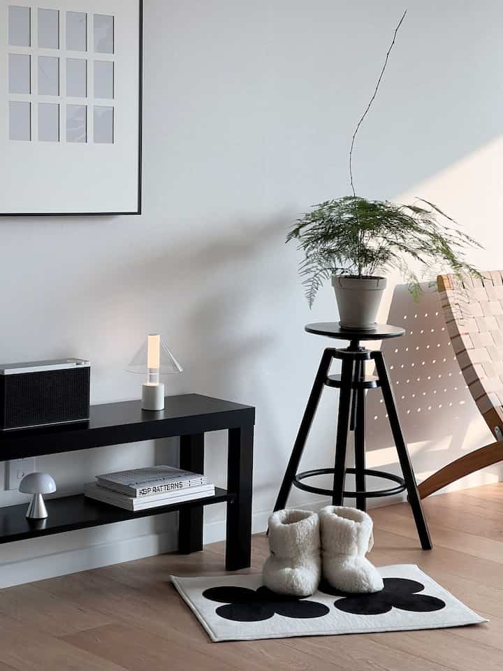 白と黒のナチュラルトーンのシンプルな一人暮らし空間、バルコニー横に小さなテーブルと植物が配置された落ち着いたリビング
