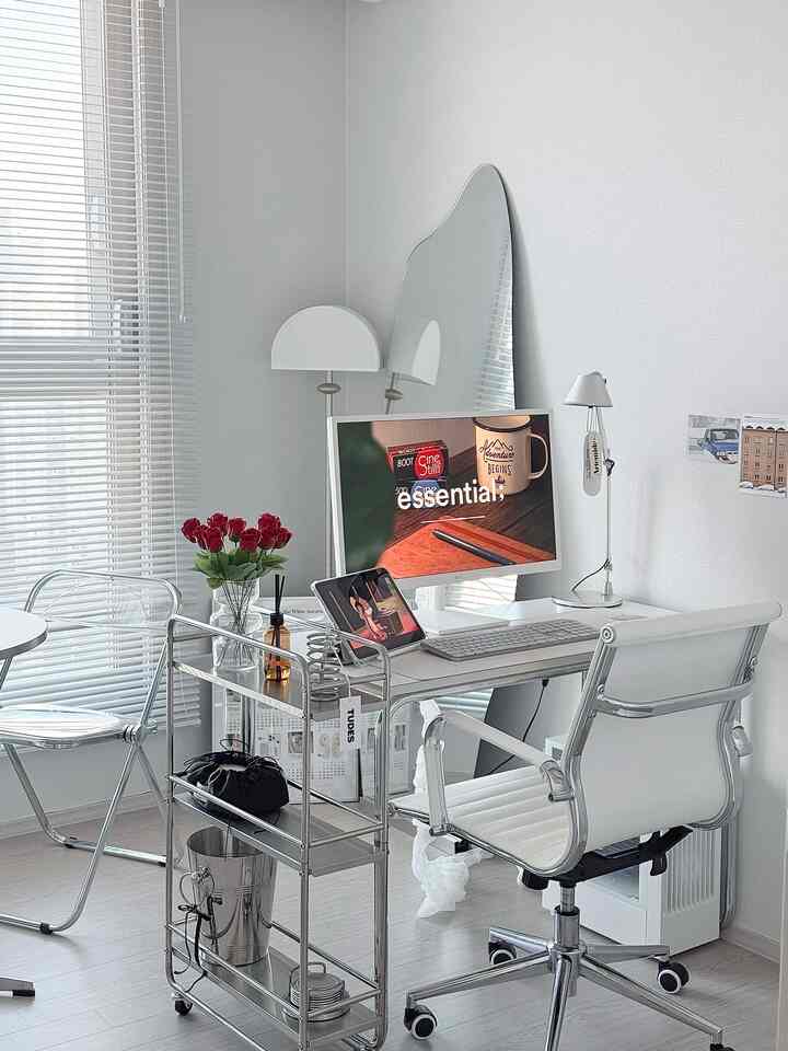 ホワイトトーンを基調とした書斎、ホワイトのデスクとチェア、クロームのトロリー、バラの花瓶が配置されたモダンなインテリア