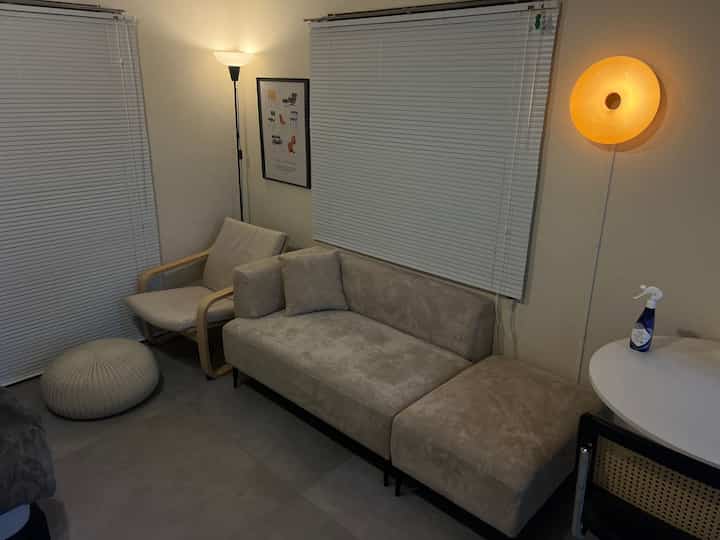 ベージュ調のリビング、ソファとアームチェア、オットマンが配置された落ち着いた雰囲気の空間