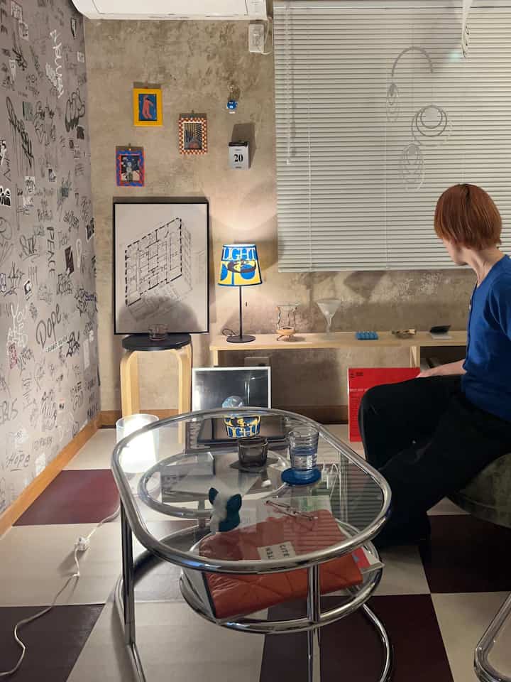 Retro-style living room with vintage concrete wallpaper and graffiti wall decor, featuring metal glass coffee table and warm indirect lighting creating cozy ambiance